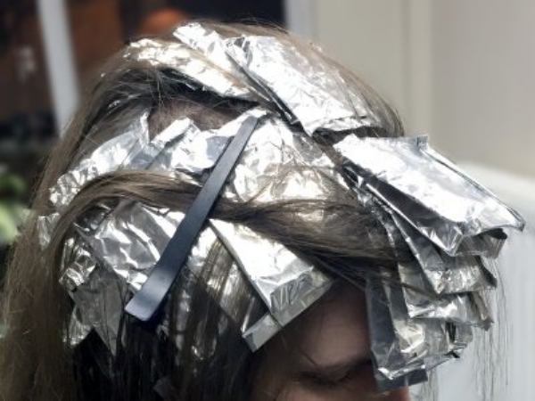 A person with their hair in foils during application of hair dye for full head highlights