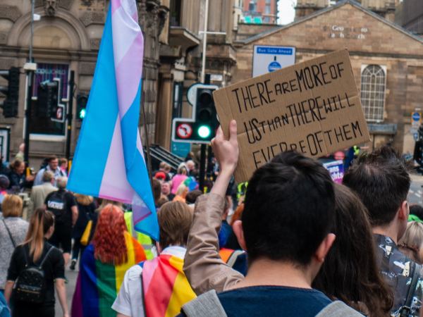 A crowd of people at a Pride march holding flags and banners